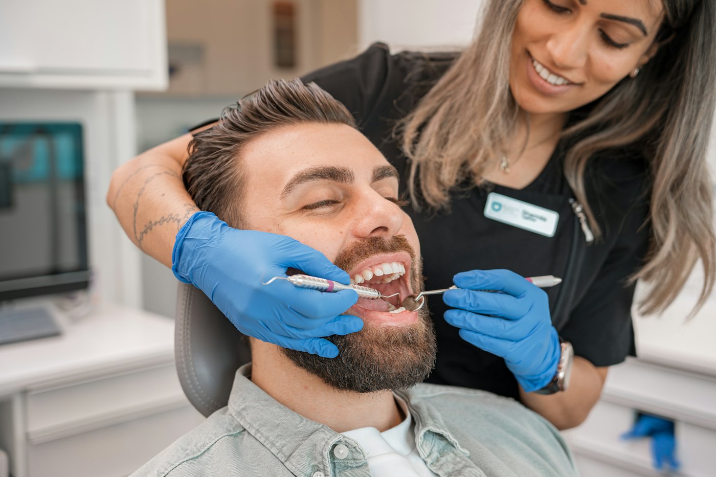 Dentist examining a smiling patient's teeth during a dental check-up